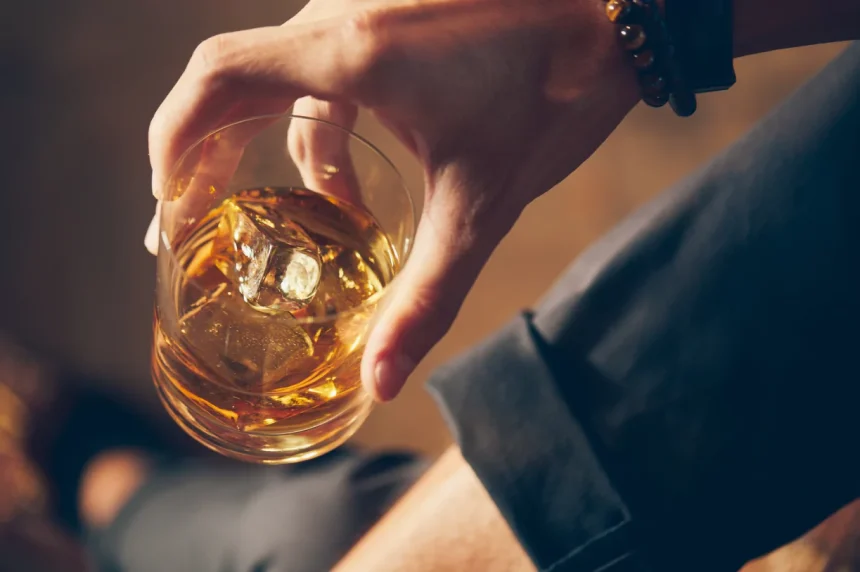 66e352d5ebb14f8672616e37 A close up of a person holding a whiskey glass with ice